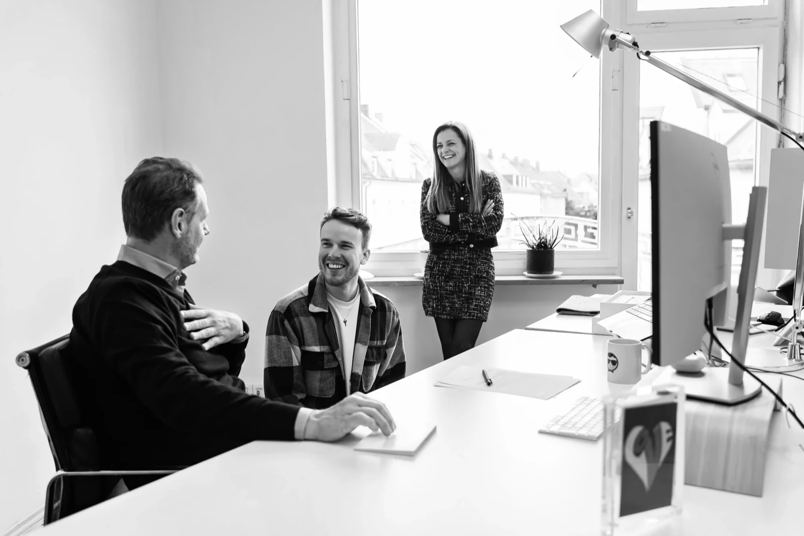 Drei Mitarbeitende arbeiten gemeinsam im Büro der GRAPEVINE München GmbH.